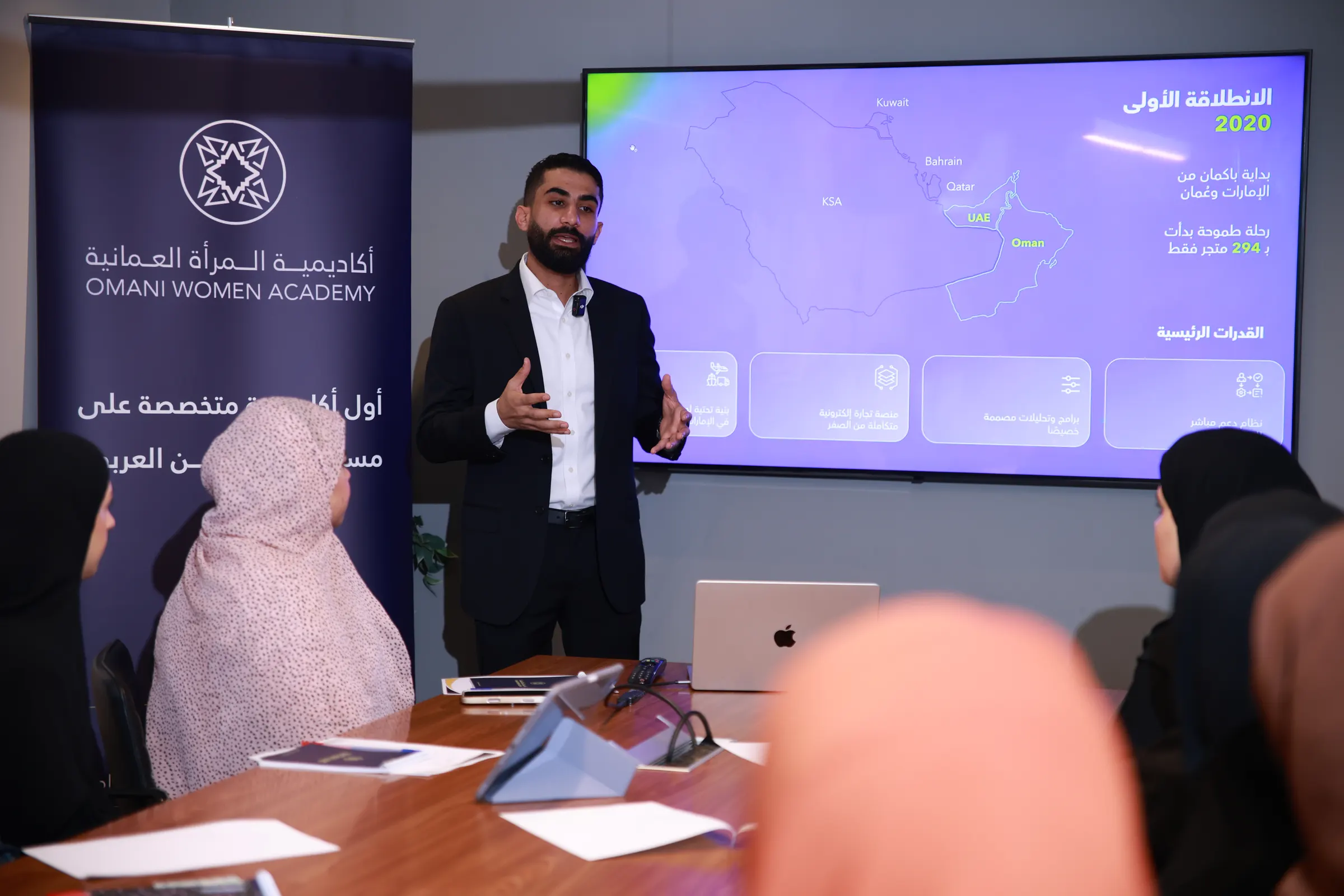 مدرّب يقدّم عرضًا لمجموعة من المشاركات حول طاولة في جلسة تدريبية